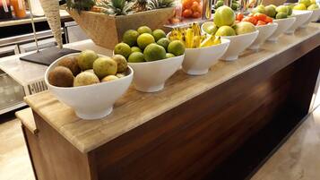 Mostrador de buffet con diversas frutas y verduras dispuestas en cuencos.