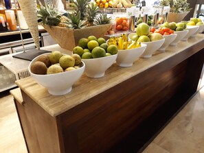 A buffet counter with various fruits and vegetables arranged in bowls.