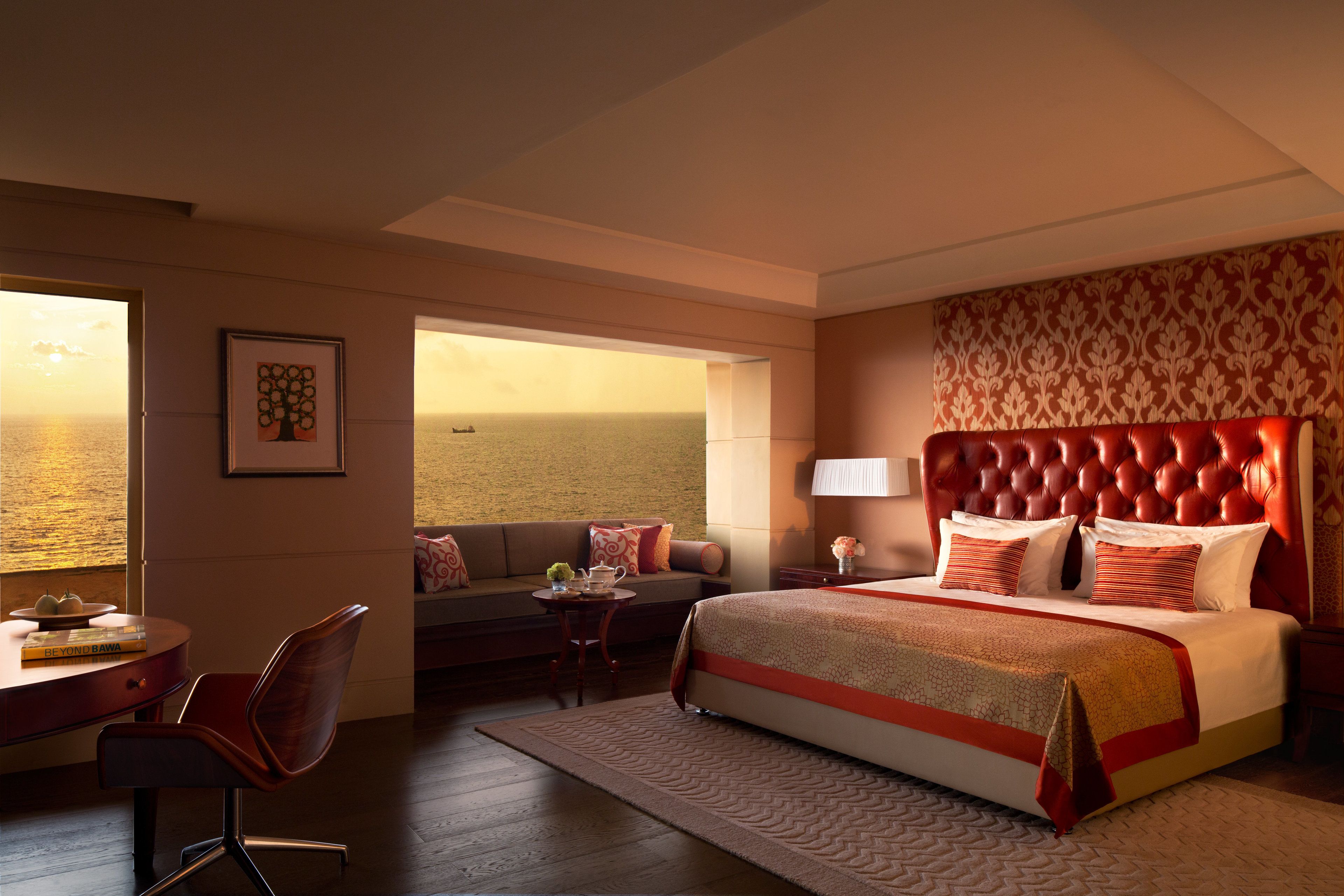 Habitación de hotel con una cama grande, un sofá, un escritorio y vistas al mar.