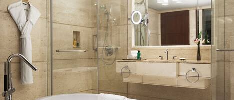 Un baño moderno con ducha envuelta en vidrio, una bañera independiente y un tocador con espejo.
