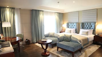 Een hotelkamer met een groot bed, twee fauteuils, een kleine tafel en een bureau met een lamp.