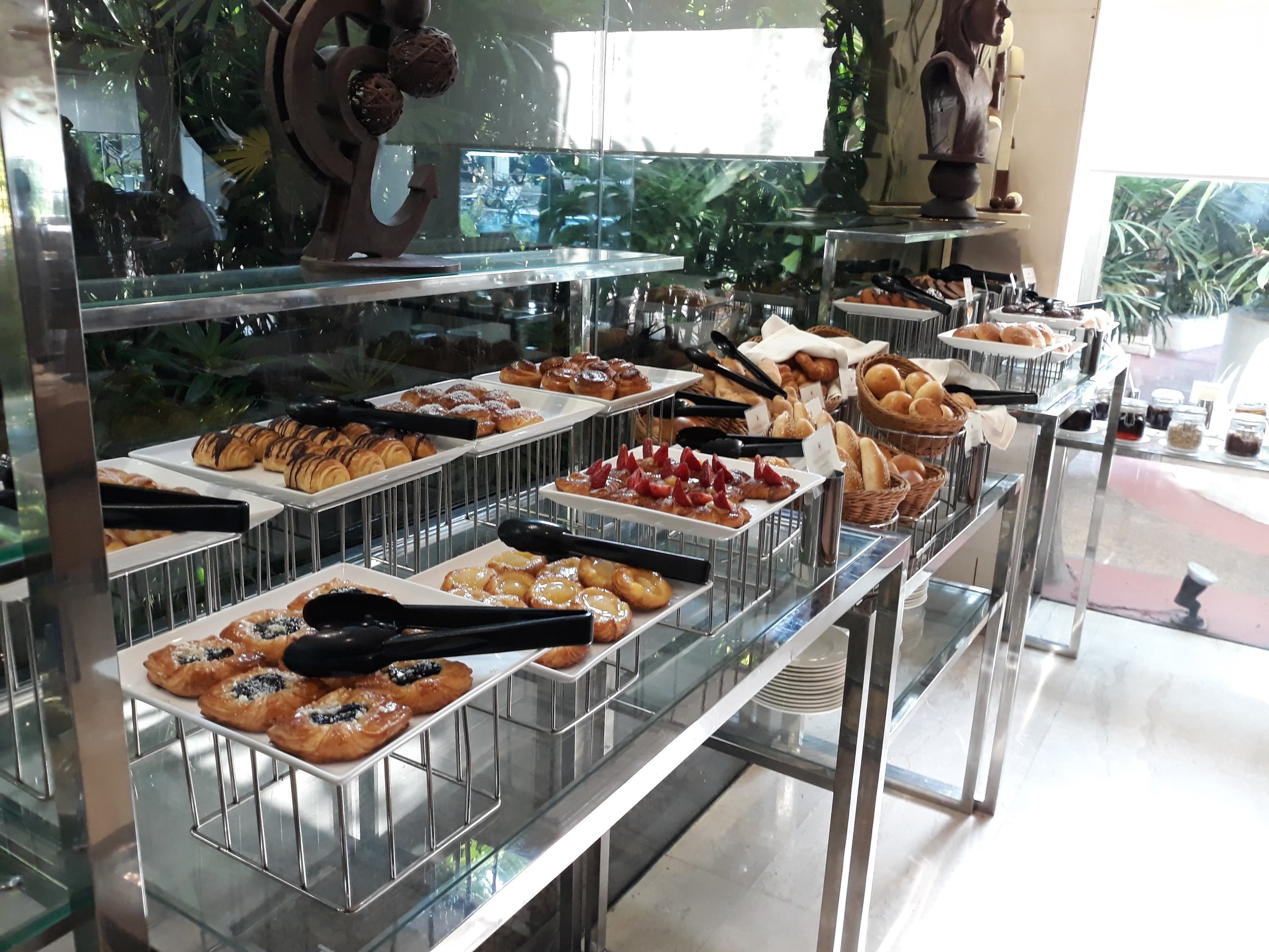 A buffet with various pastries and bread displayed on glass shelves.