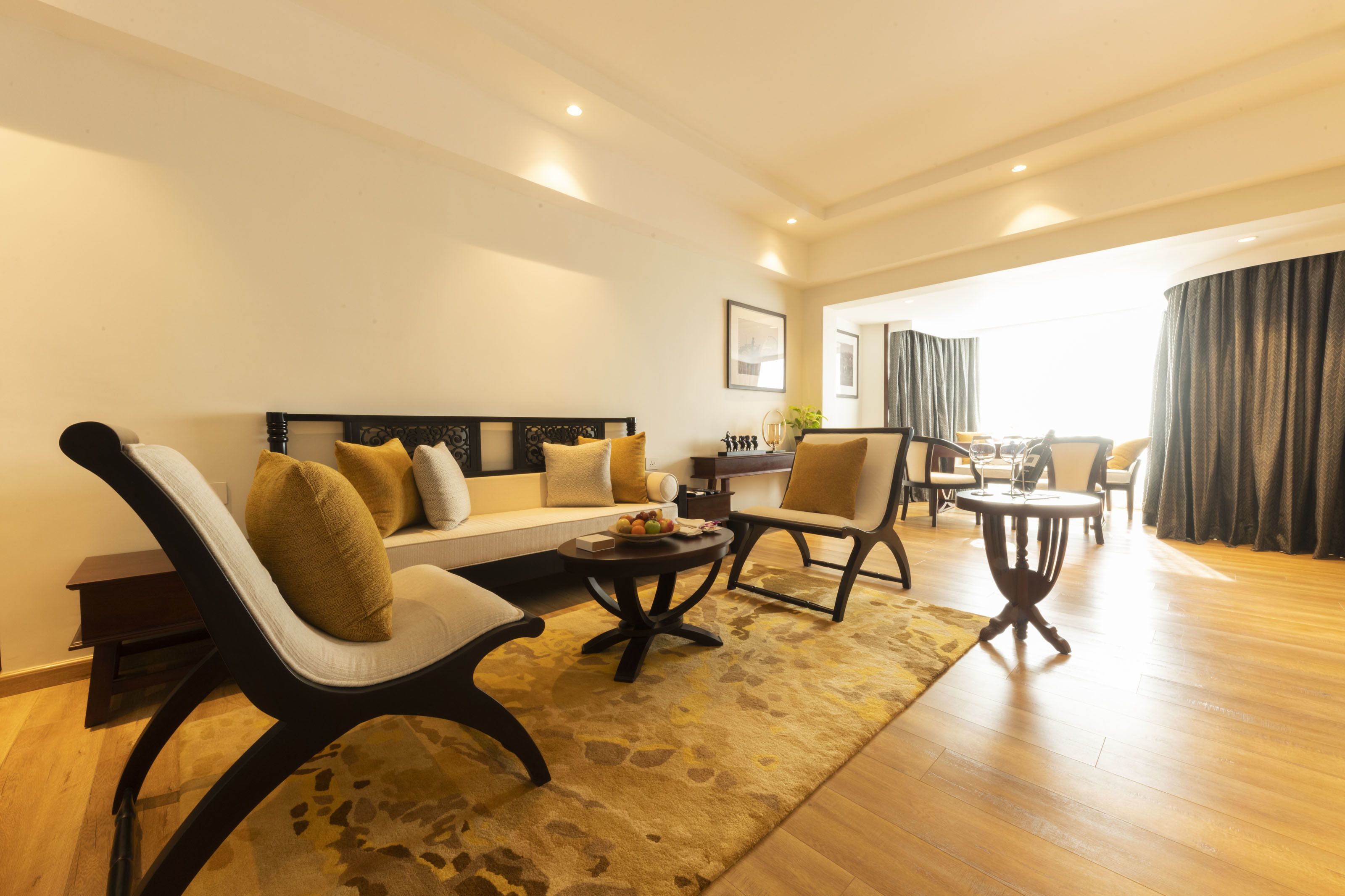 A modern living room with a sofa, two armchairs, a coffee table, and a dining area with a table and chairs.