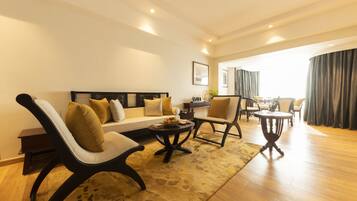 A modern living room with a sofa, two armchairs, a coffee table, and a dining area with a table and chairs.