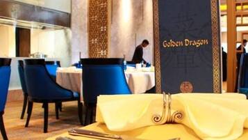 A restaurant setting with a table set for dining, a menu stand, and a person in the background.