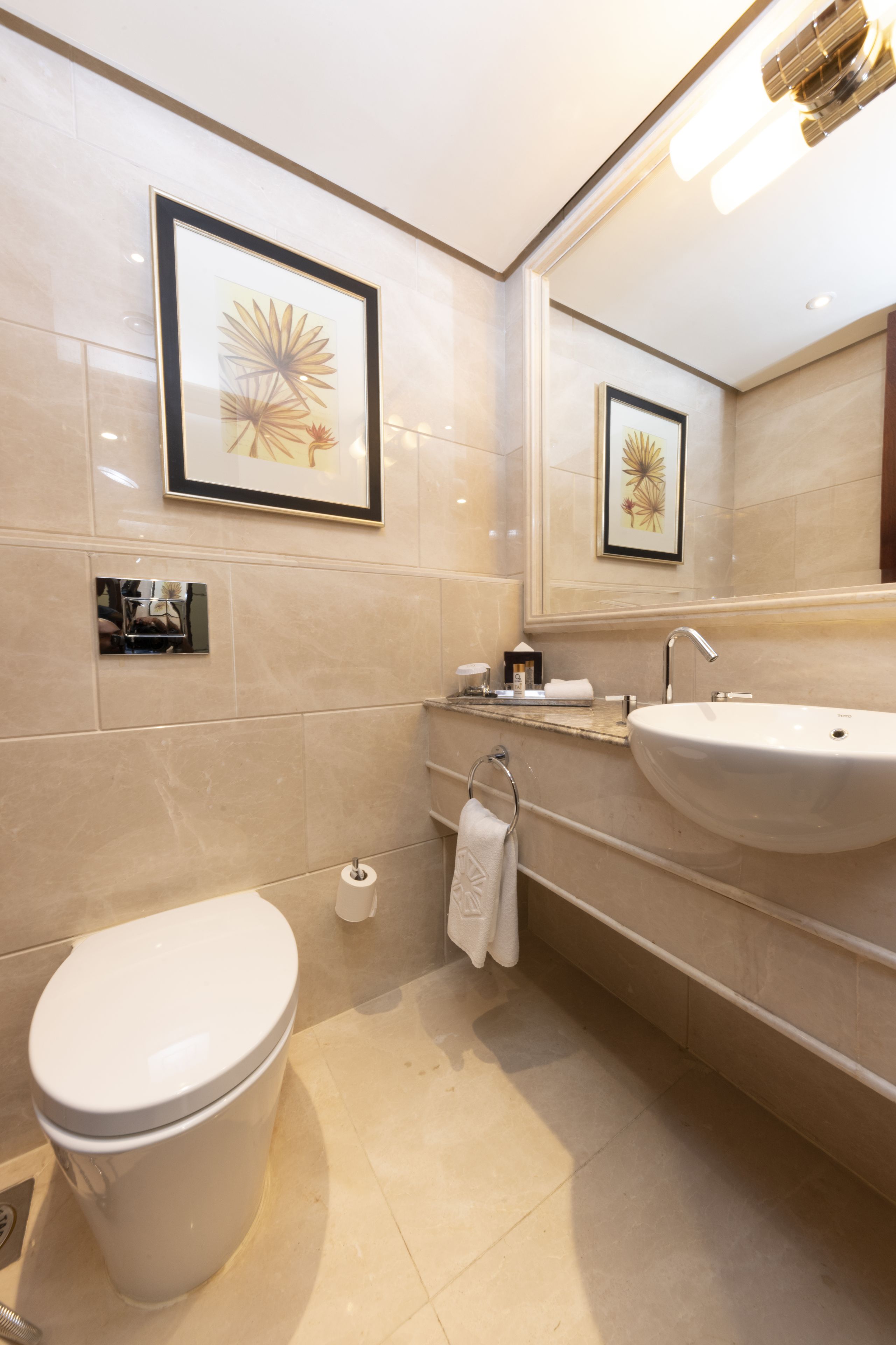 Un baño moderno con inodoro, lavamanos y un cuadro en la pared.