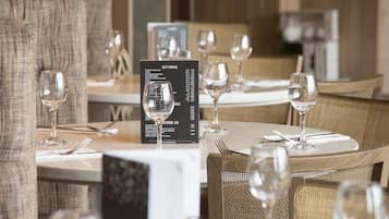 Un ambiente de restaurante con mesas dispuestas para comer, incluyendo copas de vino, cubiertos y menús.