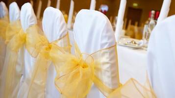 Filas de sillas blancas con cintas amarillas, señal de un ambiente para un evento formal.