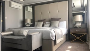 Un dormitorio moderno con una cama grande, una mesita de noche, una lámpara y una silla.