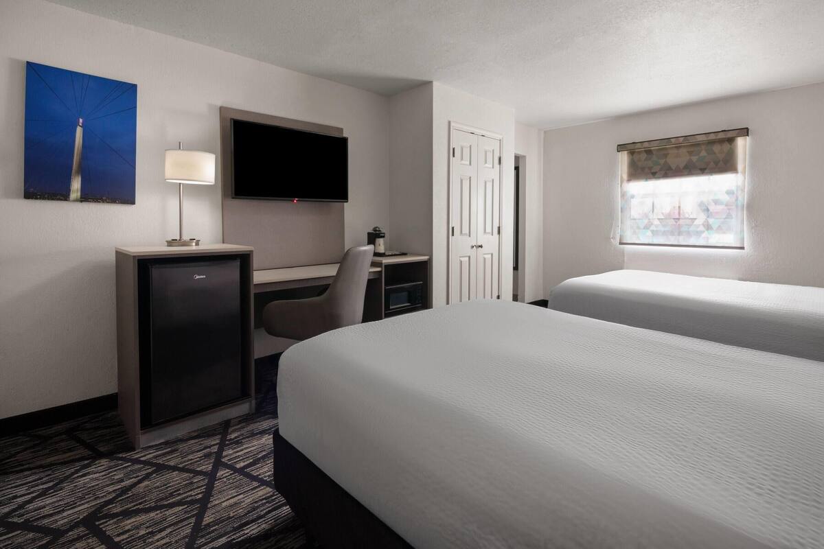 A hotel room with a bed, desk, TV, and a window with a view.