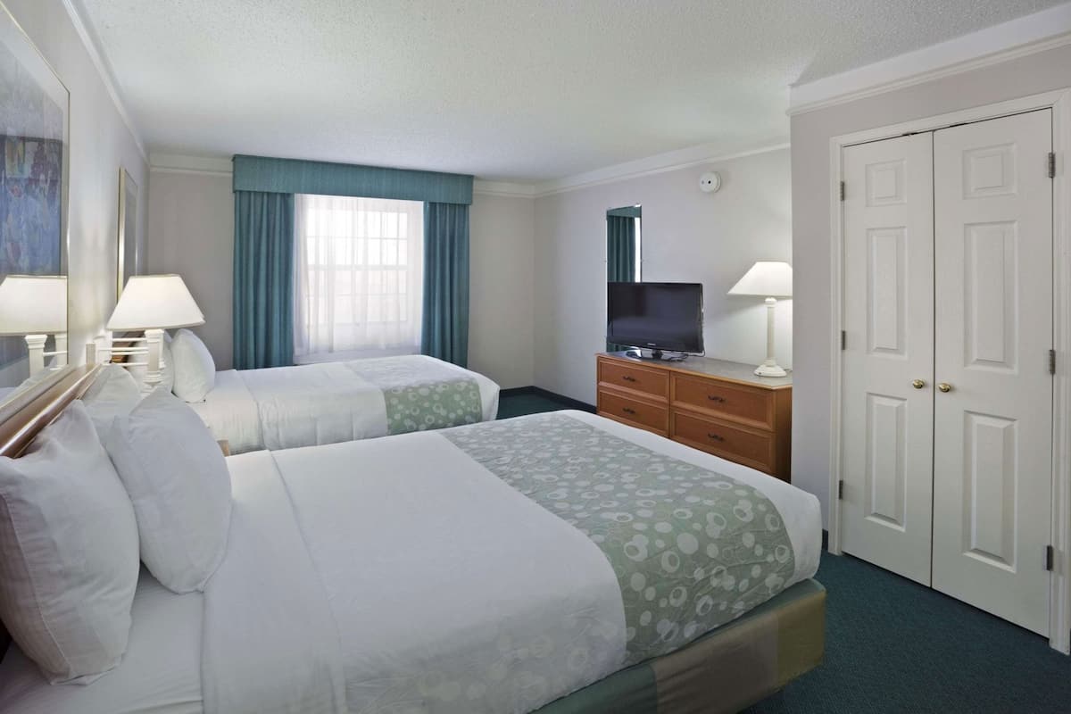 A hotel room with two beds, a TV, a dresser, and a wardrobe.