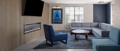 A modern living room with a flat-screen TV, a fireplace, a sofa, and a coffee table.