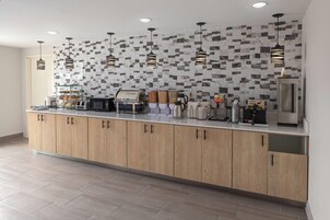 Una cocina moderna con armarios de madera, salpicadero de mármol e iluminación colgante.