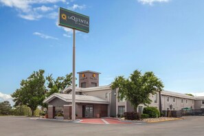 A hotel with a prominent sign, a central entrance, and a parking lot.