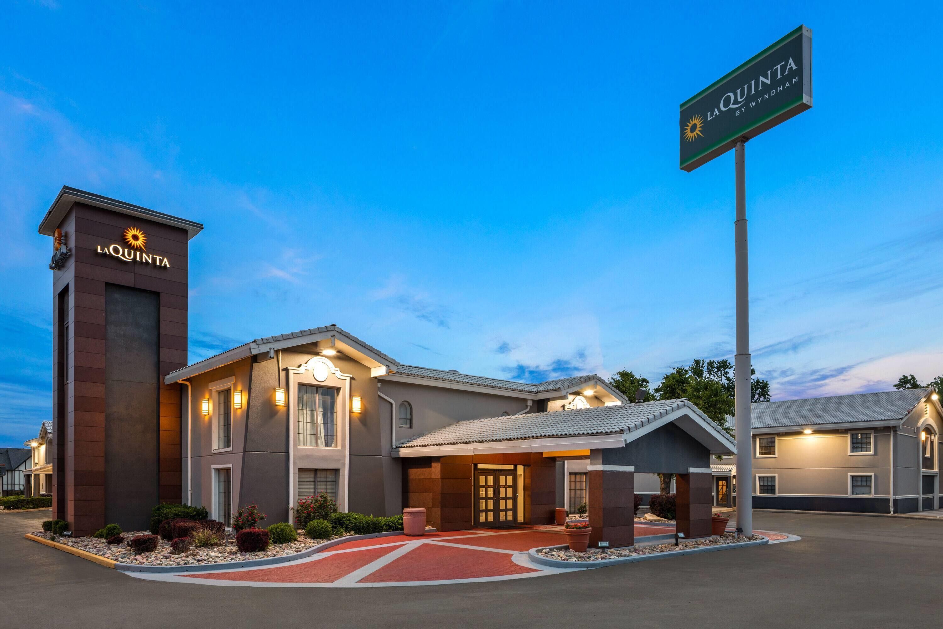 A hotel with a prominent sign, a well-lit entrance, and a landscaped driveway.