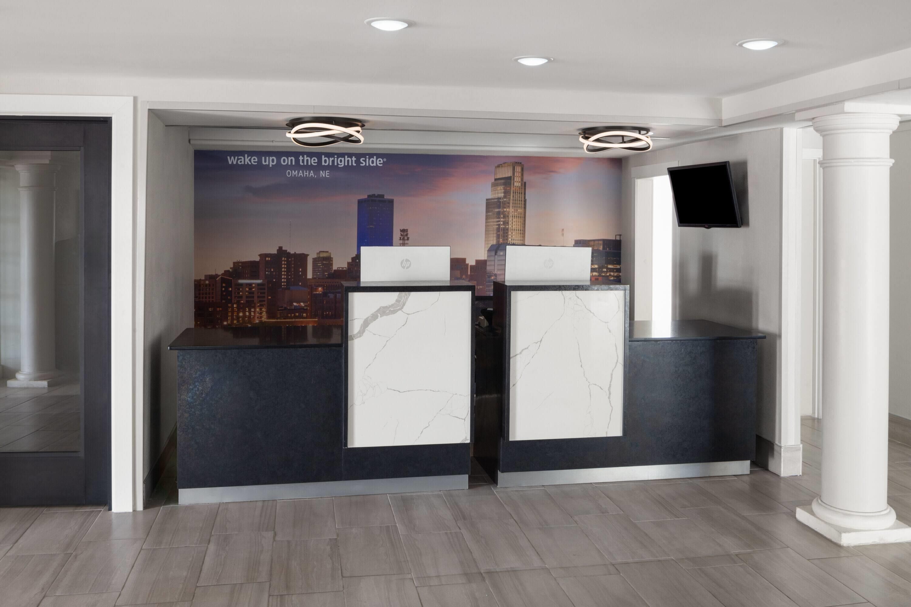 Un mostrador de recepción con un mural de la ciudad, un televisor de pantalla plana y un diseño moderno.