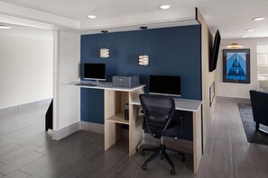 A modern office space with a desk, two monitors, a printer, and a chair.
