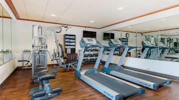 A gym with treadmills, weight machines, and dumbbells.