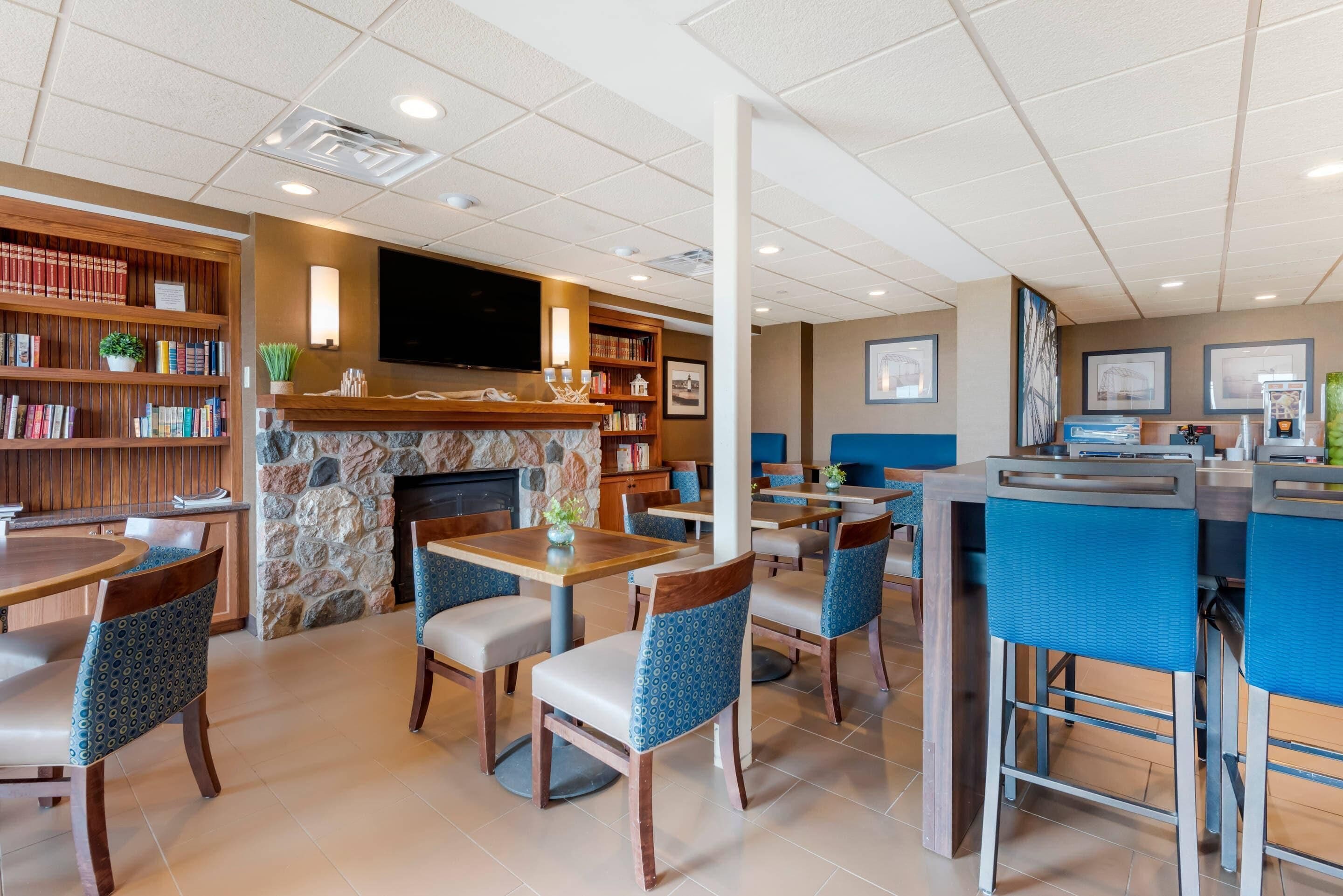 Un hall d’hôtel doté d’une cheminée, de bibliothèques et d’un espace bar.