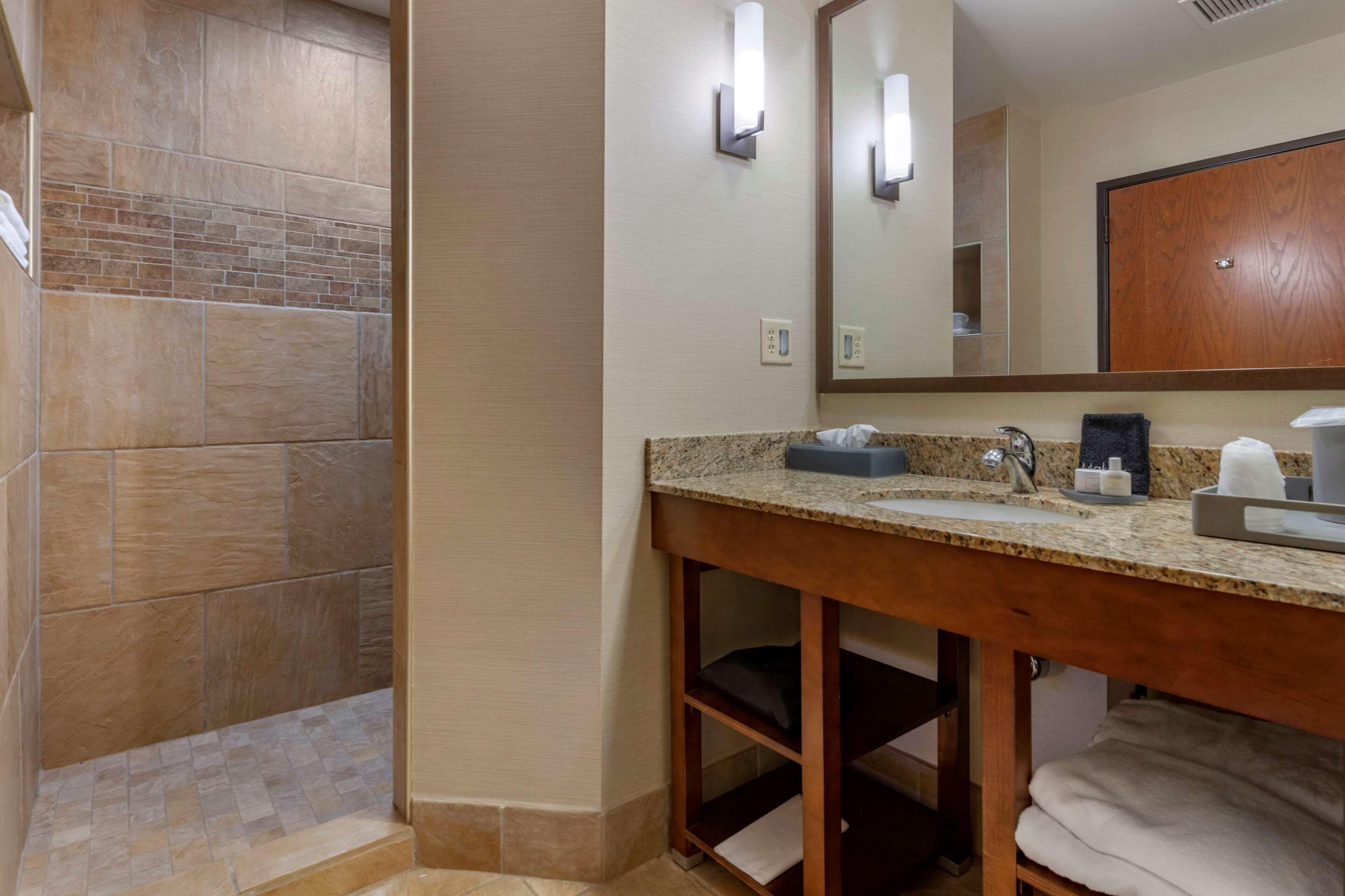 A bathroom with a shower, a sink with a mirror, and a towel rack.