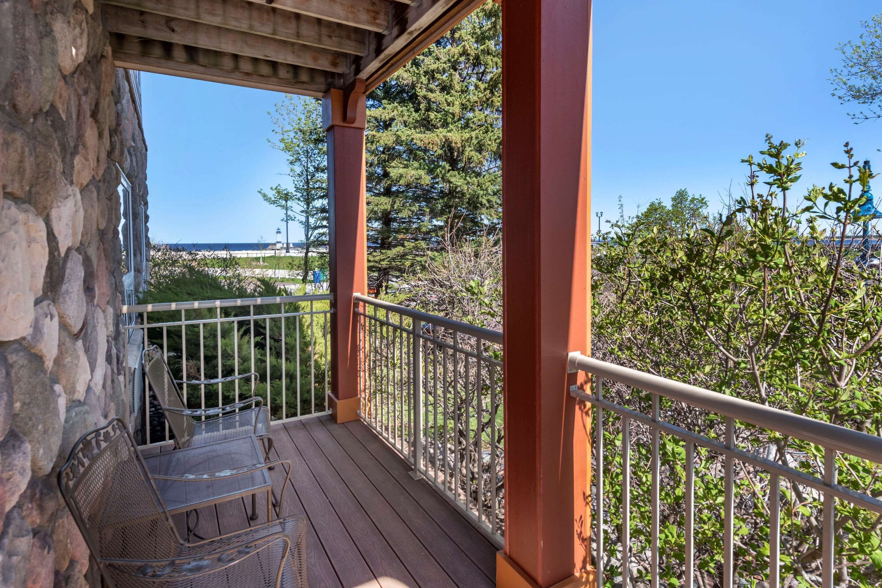 A balcony with stone walls, metal railings, and metal chairs.