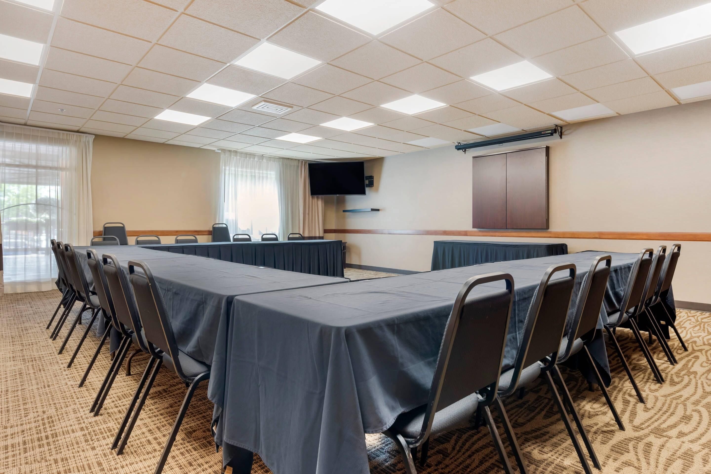 A conference room with a long table, chairs, a TV, and a cabinet.