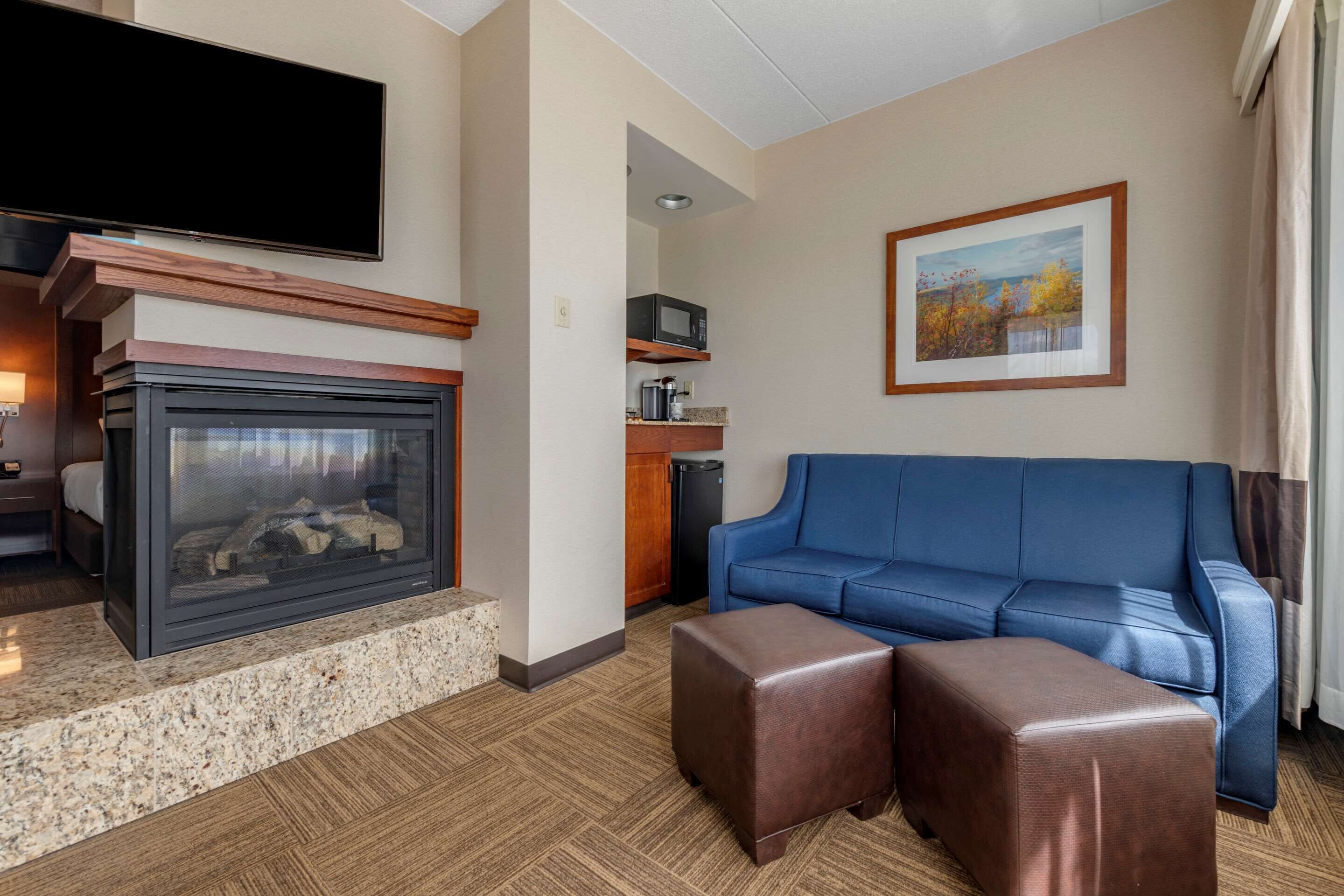 Una sala de estar moderna con chimenea, un sofá azul y un televisor de pantalla plana.
