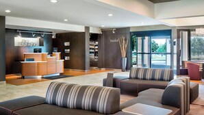 A modern lobby with a reception desk, seating area, and a view of the outdoors.