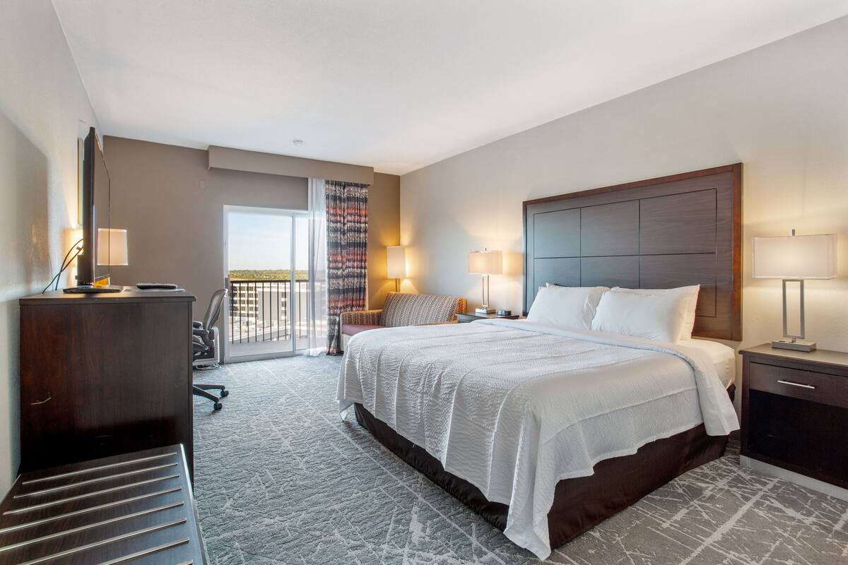 Une chambre d’hôtel avec un grand lit, un bureau, une chaise et une vue sur la ville.