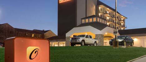 A hotel with a sign reading "Orangewood Inn & Suites," a parking area with a white pickup truck, and a well-maintained lawn.
