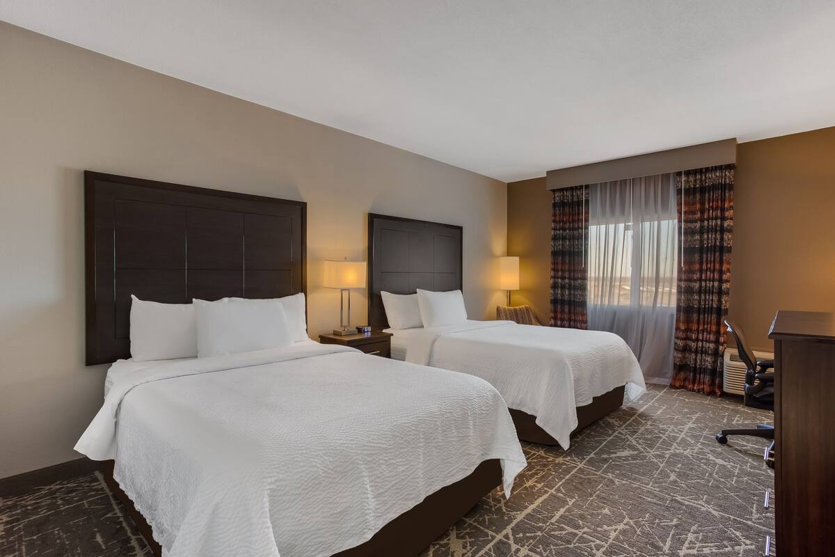 Une chambre d’hôtel avec deux lits, un bureau et une chaise.