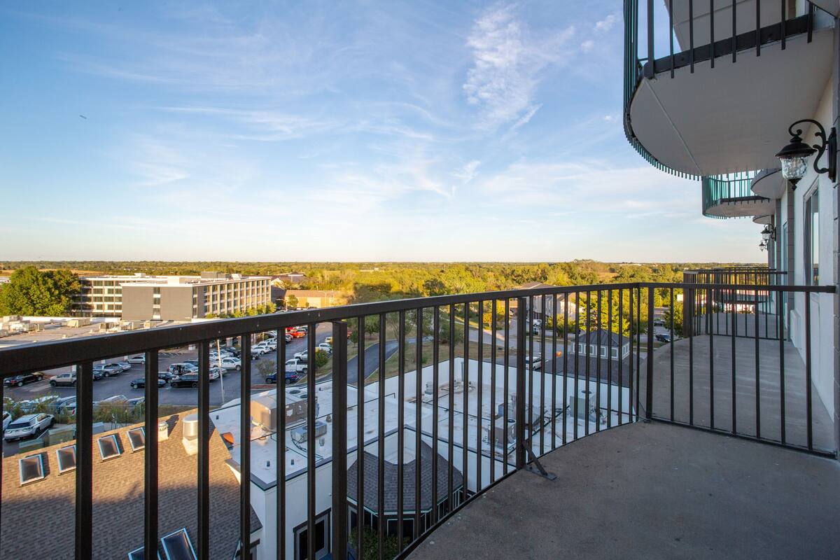 Un balcon donnant sur un parking et des immeubles.