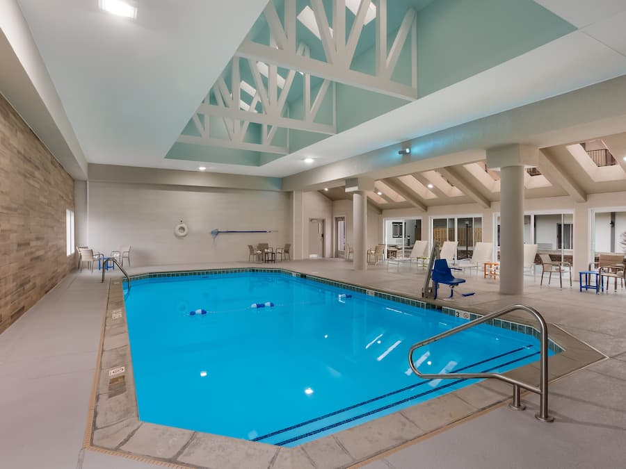 Ein Hallenbad mit klarem, blauem Wasser, umgeben von gefliestem Boden und weißen Wänden.