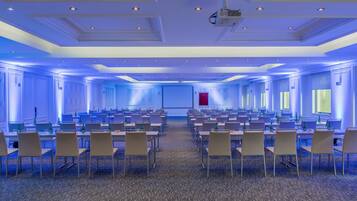 A conference room with rows of tables and chairs, a projector, and a red accent wall.