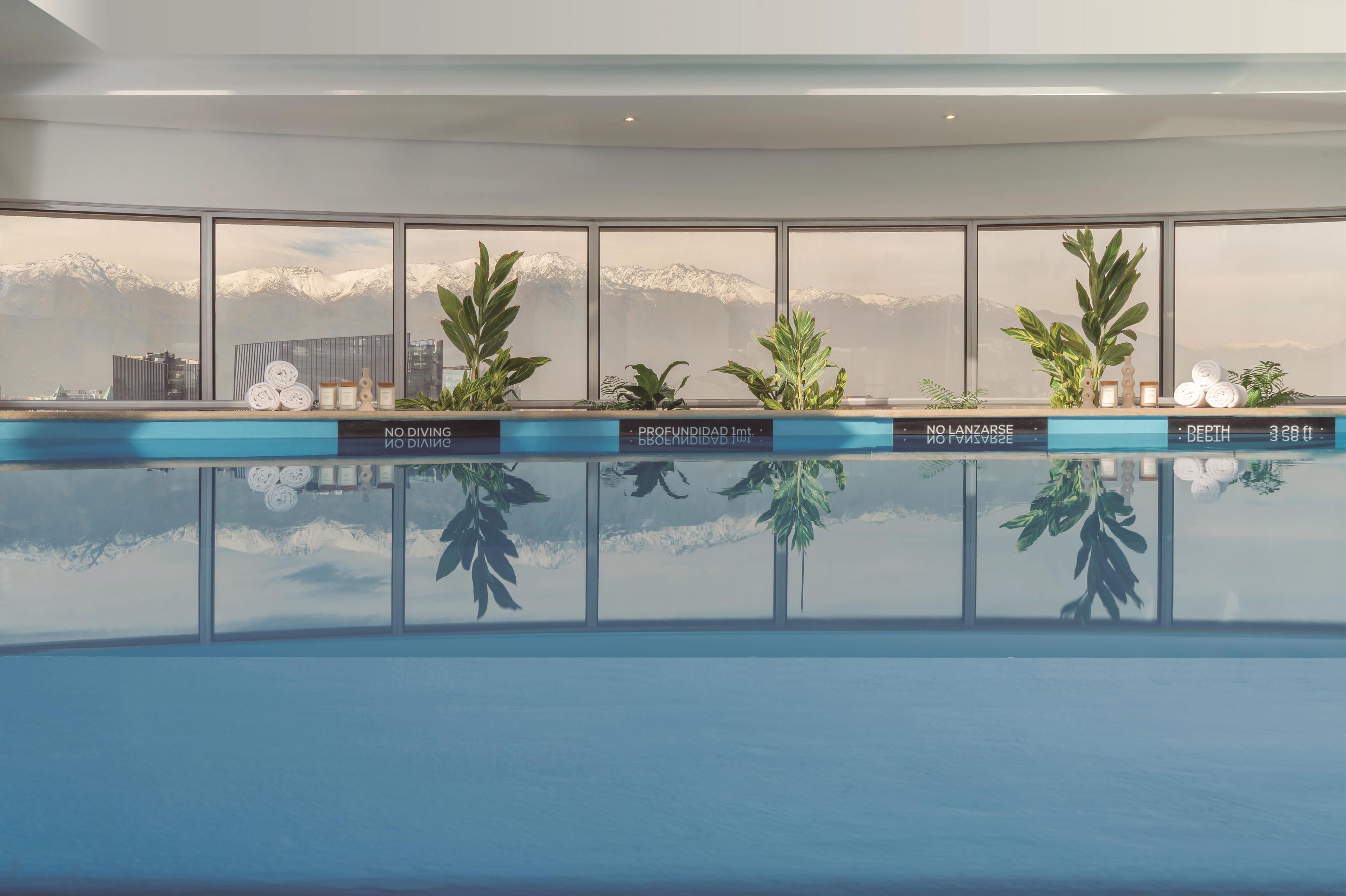 A modern indoor pool with large windows offering a view of snow-capped mountains.
