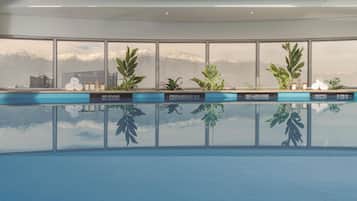 A modern indoor pool with large windows offering a view of snow-capped mountains.