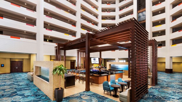 En hotellobby med en central bardisk, sittgrupper och en mönstrad matta.