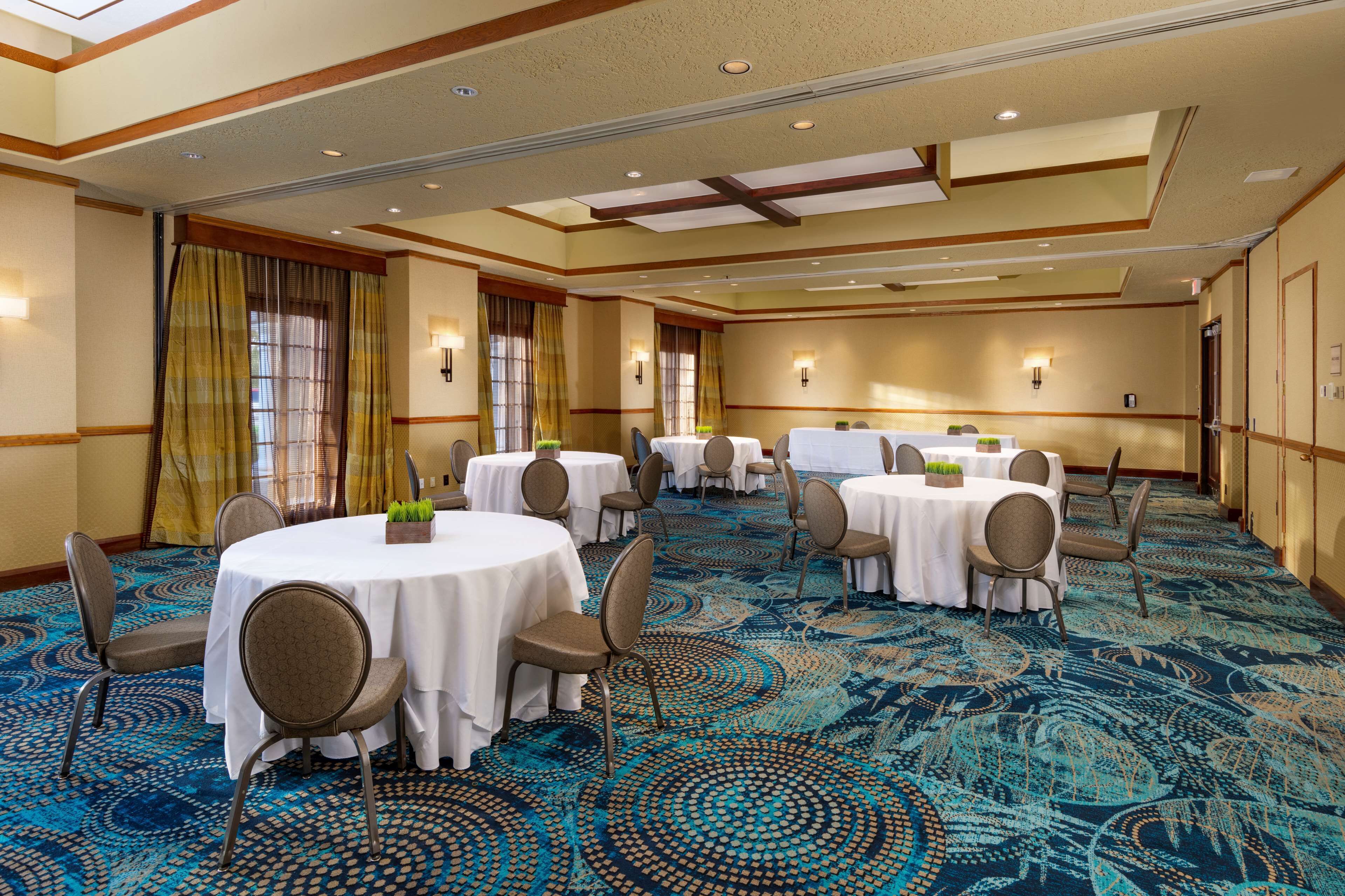 Une salle de conférence avec des tables rondes, des chaises et un tapis à motifs.