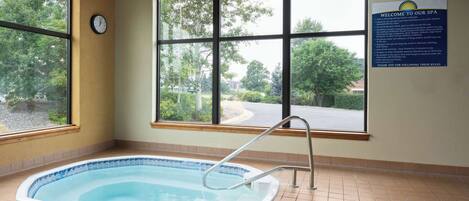 Un cuarto de spa con bañera de hidromasaje, ventanas amplias y un cartel de bienvenida.
