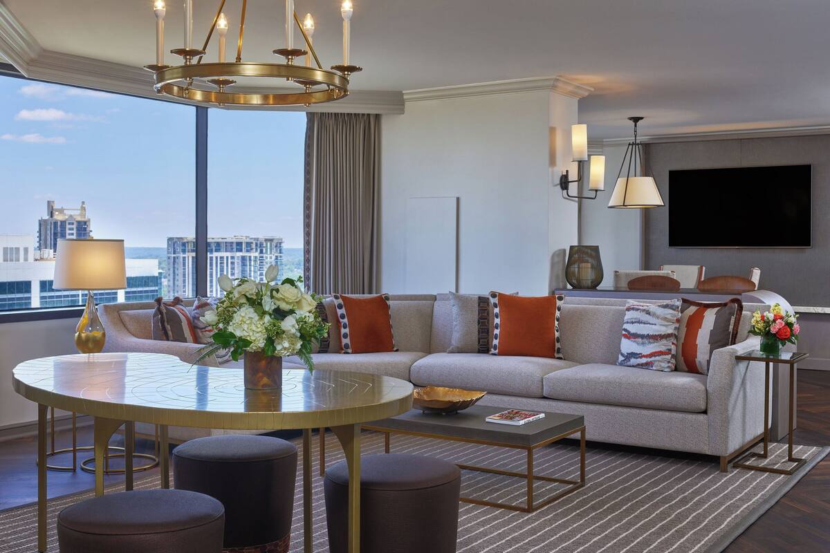 A modern living room with a round dining table, a sofa set, and a large TV mounted on the wall.
