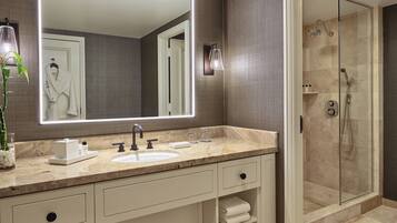 A modern bathroom with a large mirror, a sink, and a glass-enclosed shower.
