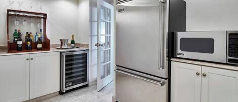 Una cocina moderna con electrodomésticos de acero inoxidable, una cava de vinos y una puerta que da a otra habitación.