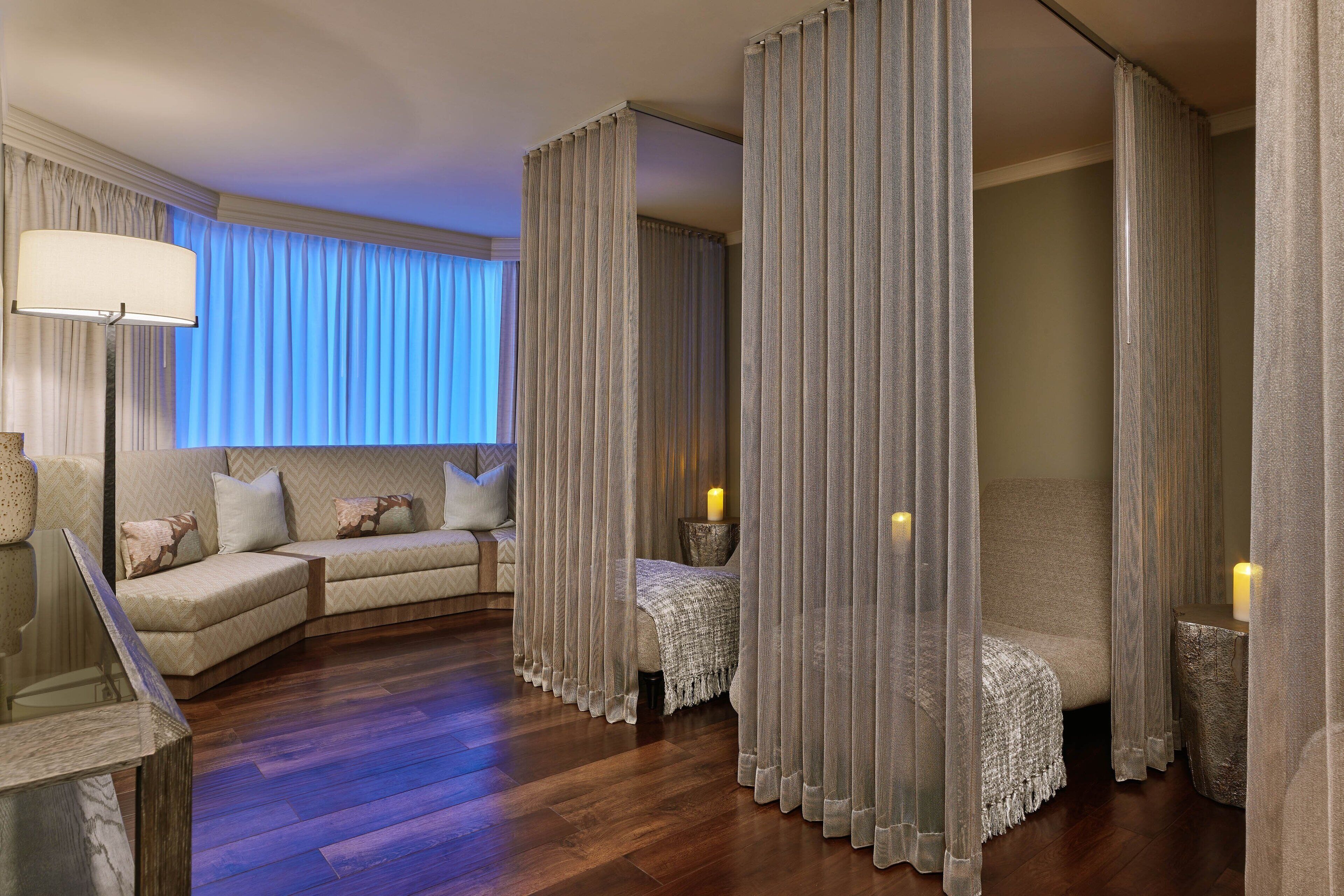 Habitación de hotel con suelo de madera, un sofá, una silla y una cama con dosel.