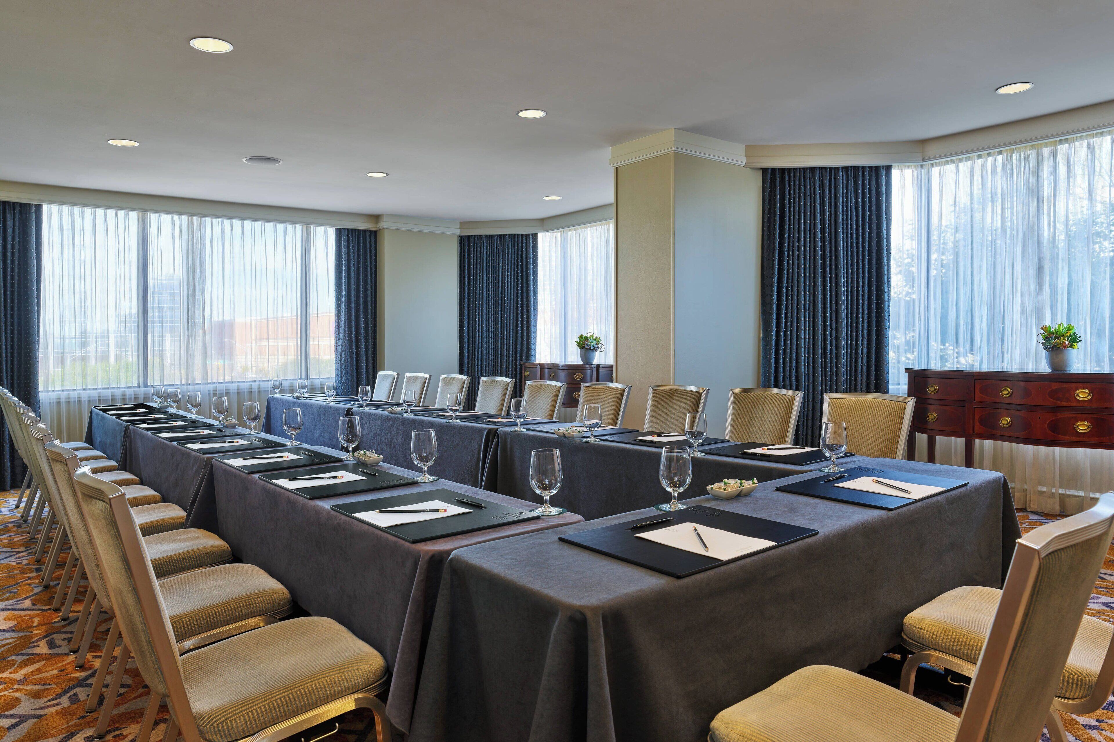 Un salón de conferencias con una larga mesa dispuesta para reuniones, rodeado de sillas.