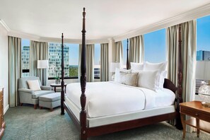 A large, four-poster bed with a view of the cityscape through floor-to-ceiling windows.