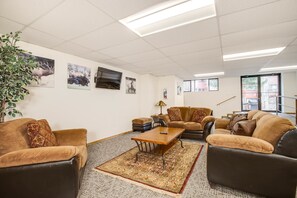 A spacious living room with a large rug, multiple sofas, a coffee table, and wall-mounted artwork.