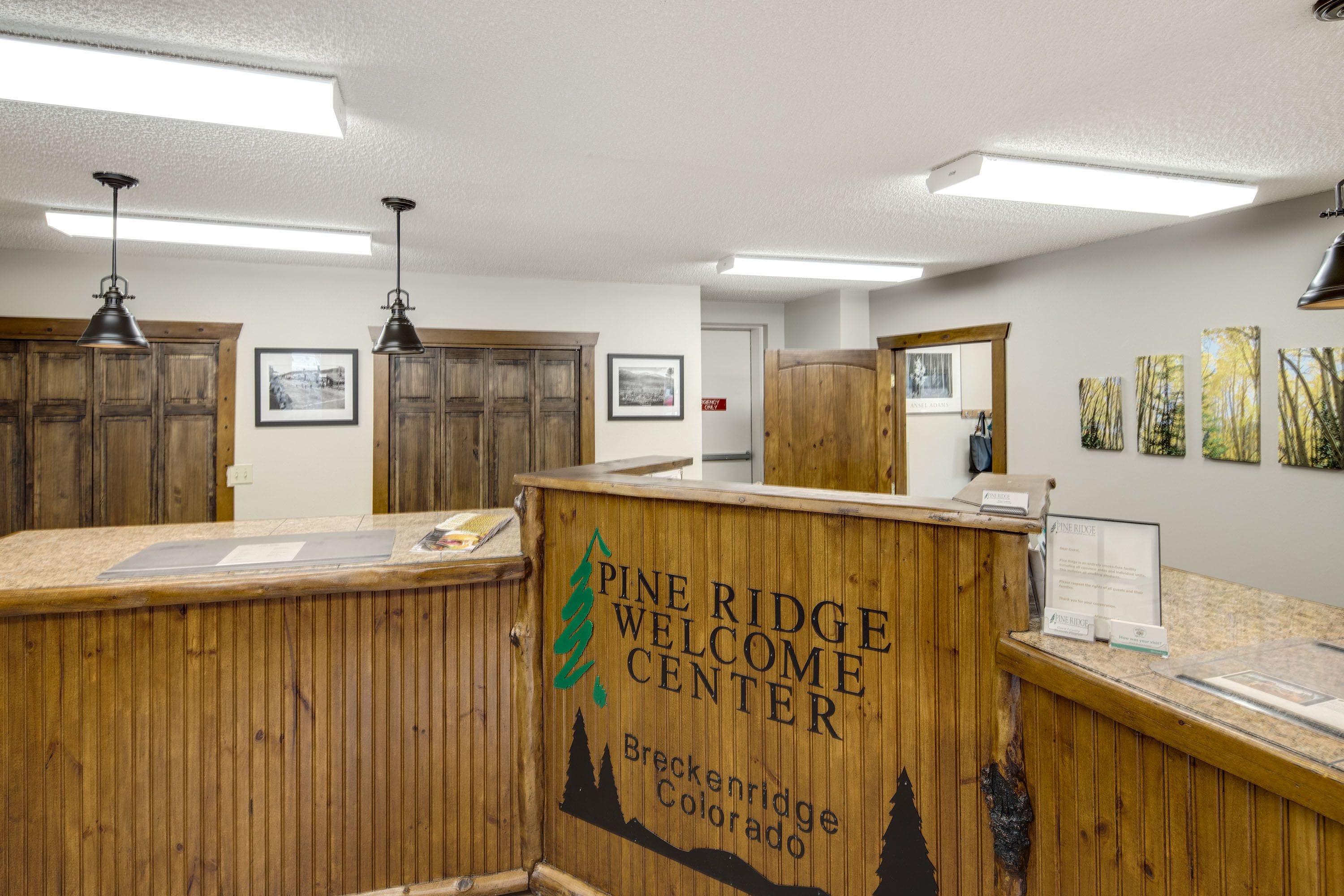 Een Pine Ridge Welcome Center met houten balies, ingelijste foto's aan de muur en een bord dat aangeeft dat het centrum in Breckenridge, Colorado, is.