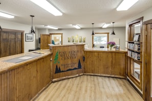 A Pine Ridge Welcome Center with wooden paneling, a reception desk, and a bookshelf.