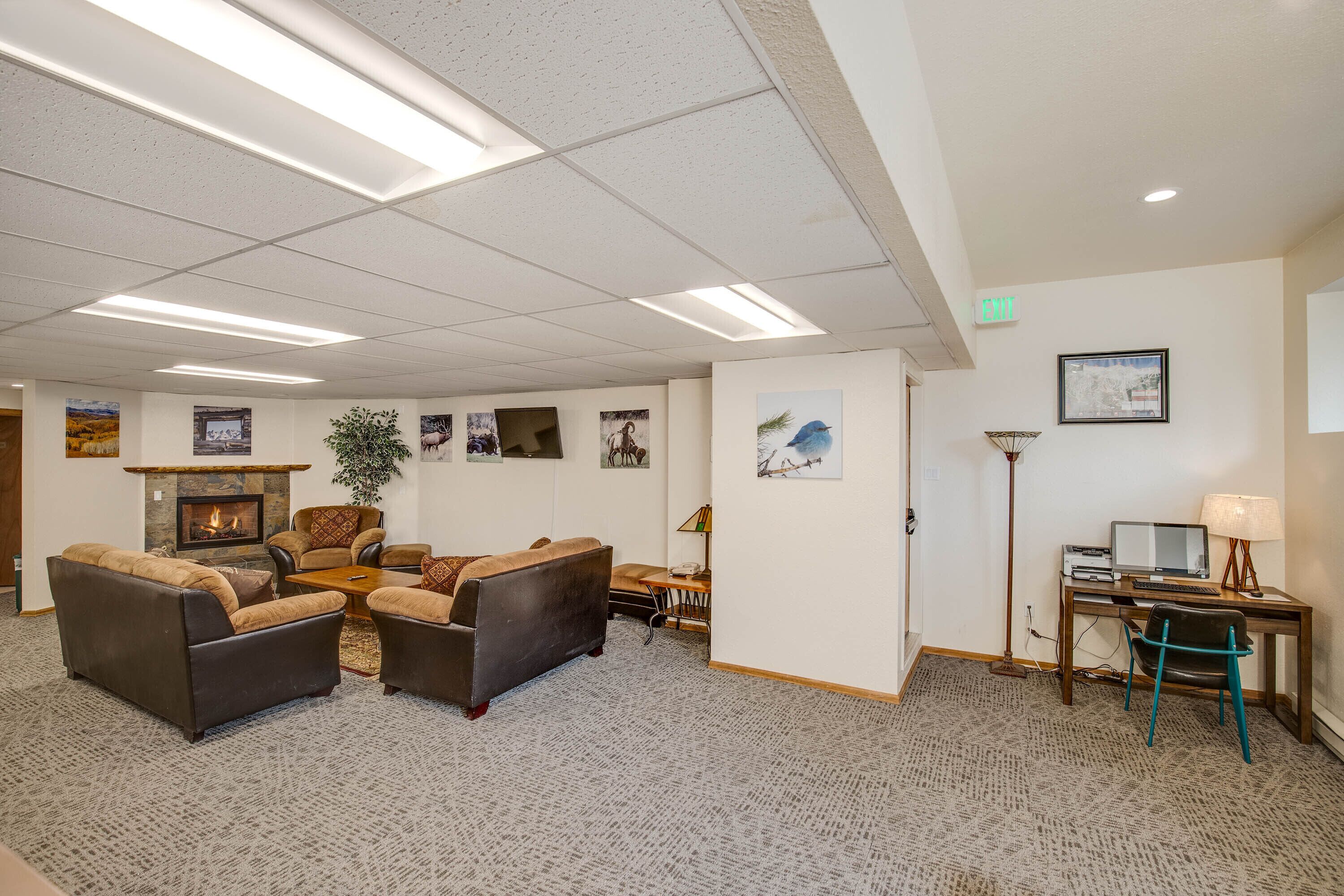 A spacious lobby with a fireplace, comfortable seating, and a desk with a computer.