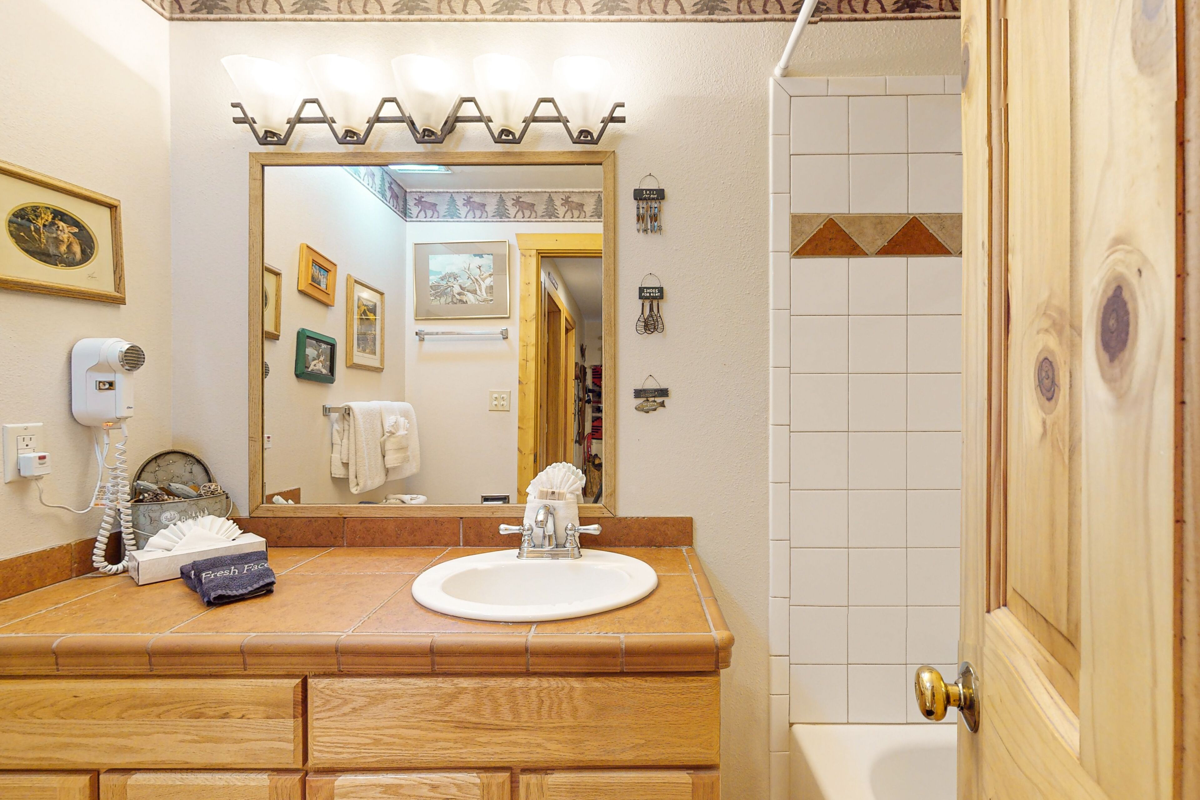 Un baño con tocador de madera, un lavabo blanco, un espejo y una zona de ducha.